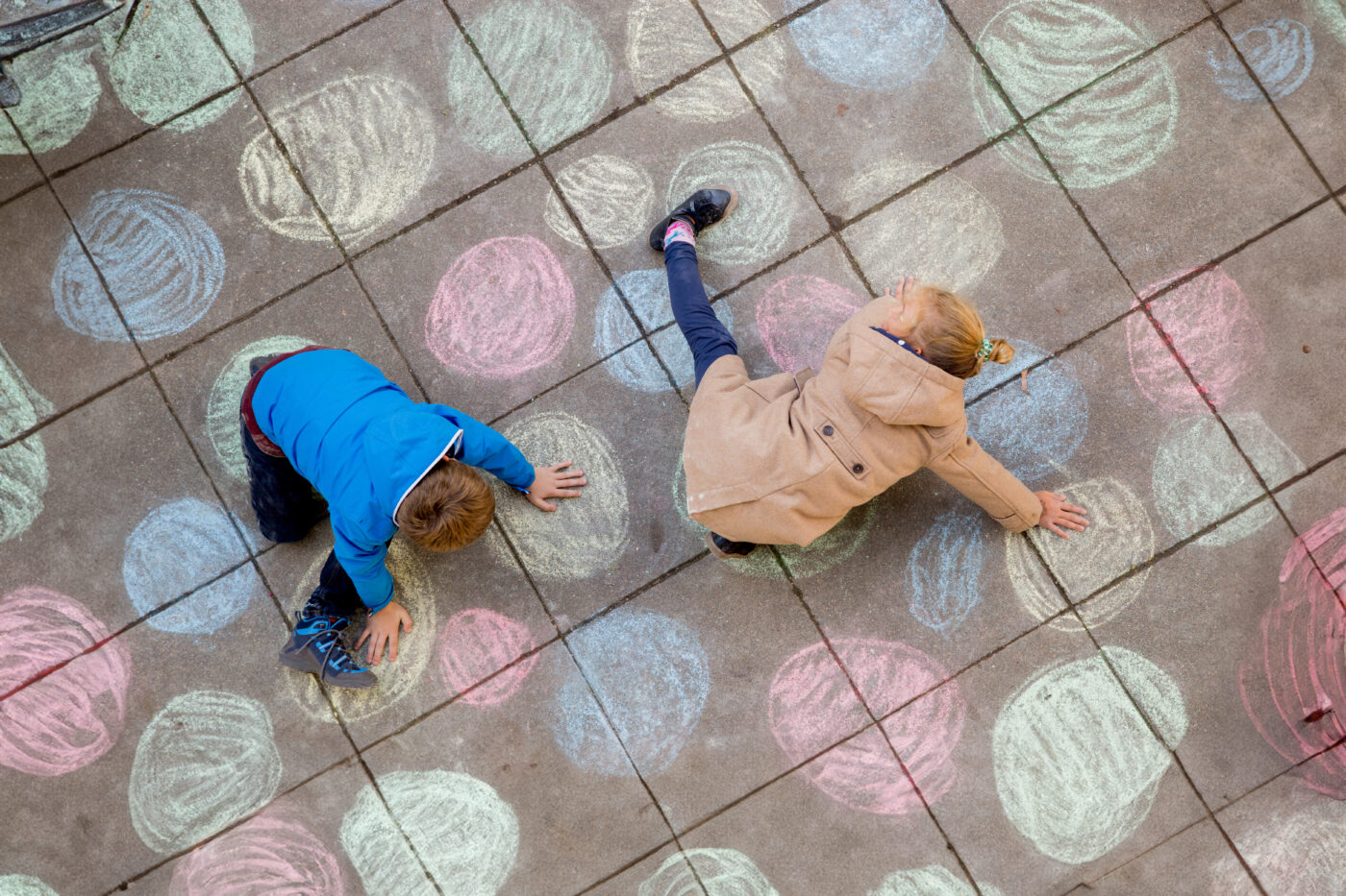 Zwei Kinder spielen mit Kreide auf dem Boden