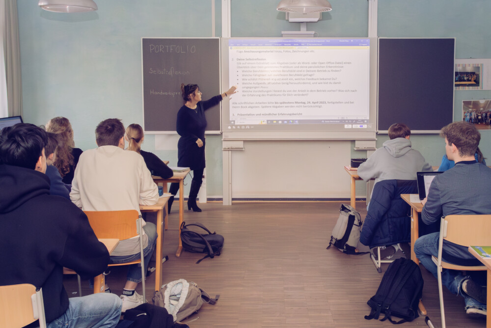 Eine Frau, die in einem Klassenzimmer vor einem Whiteboard steht